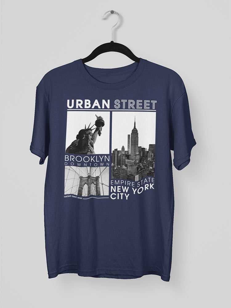 A navy blue t-shirt with a graphic of New York landmarks and text, hanging on a white hanger against a light gray background.