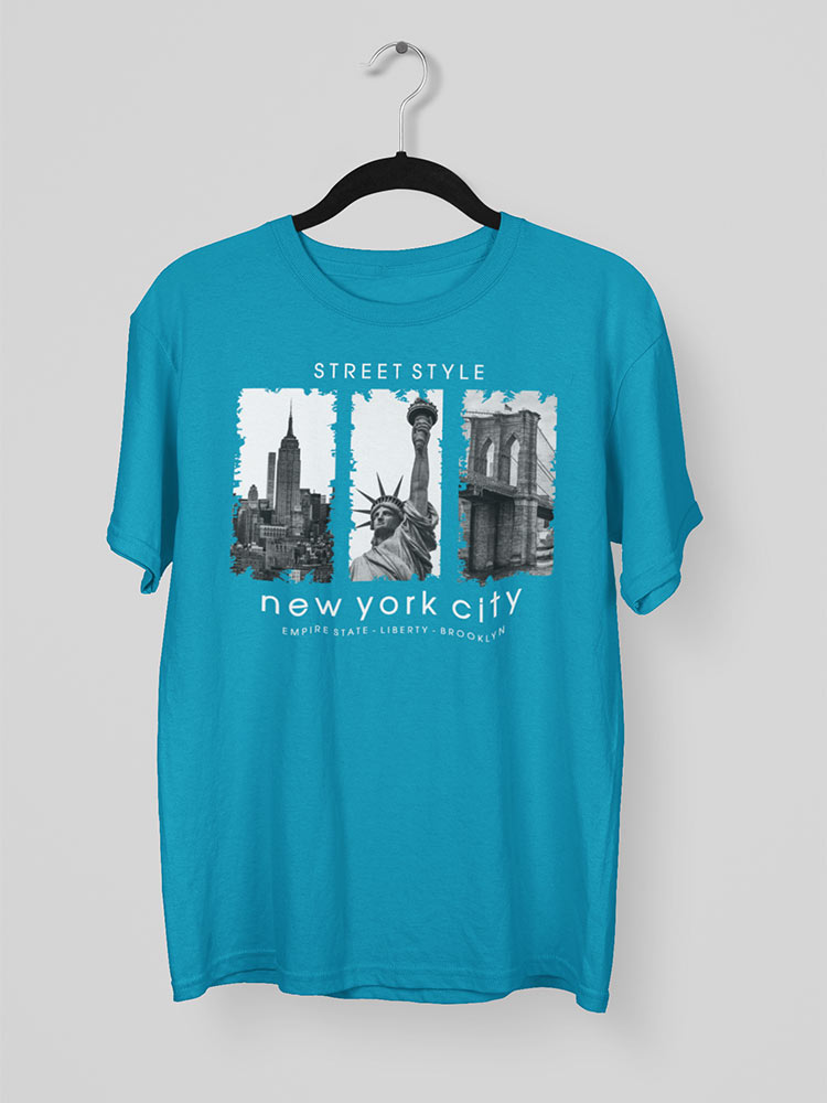 This image features a bright blue t-shirt hanging on a white hanger against a grey background, with a graphic of New York City landmarks and text.