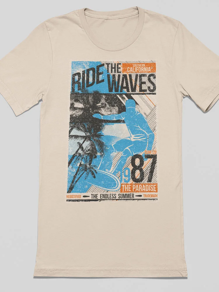 This is a beige t-shirt featuring a vintage-style graphic design with text "Ride the Waves" and "The Endless Summer." Silhouettes of palm trees and a surfer are visible.