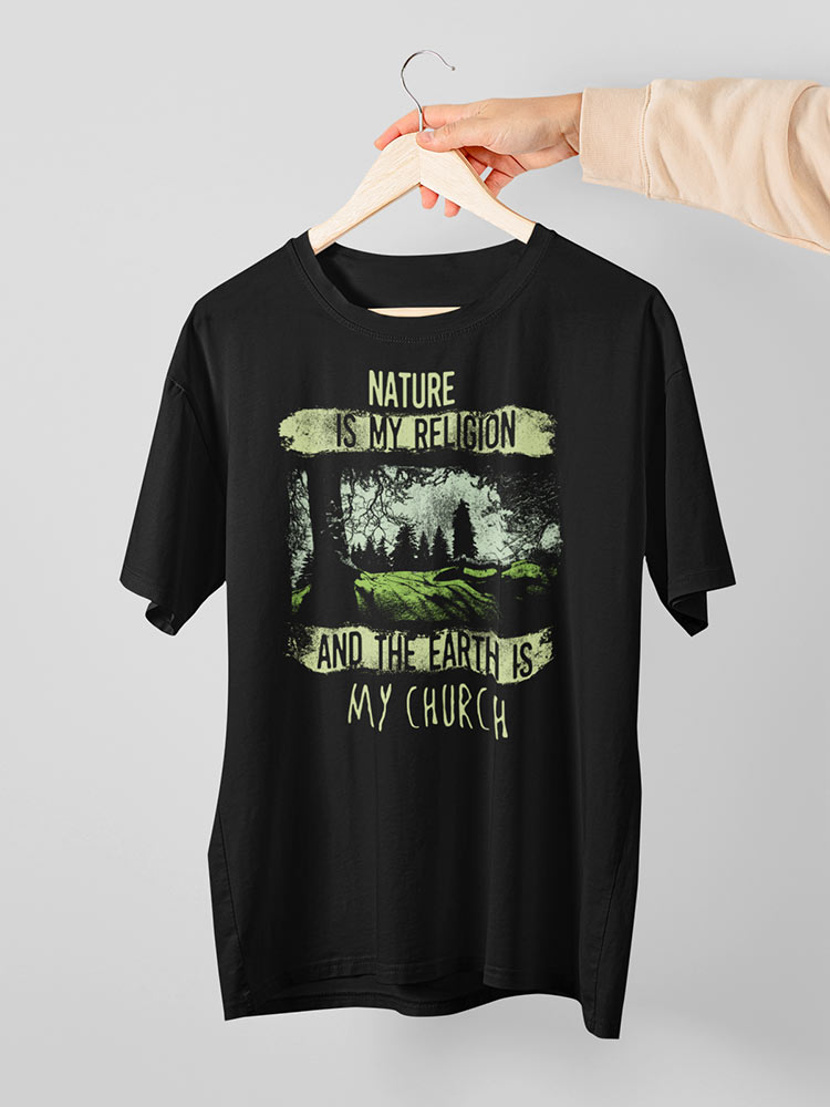 A person is holding a black t-shirt with a nature-themed print stating "NATURE IS MY RELIGION AND THE EARTH IS MY CHURCH" on a hanger.