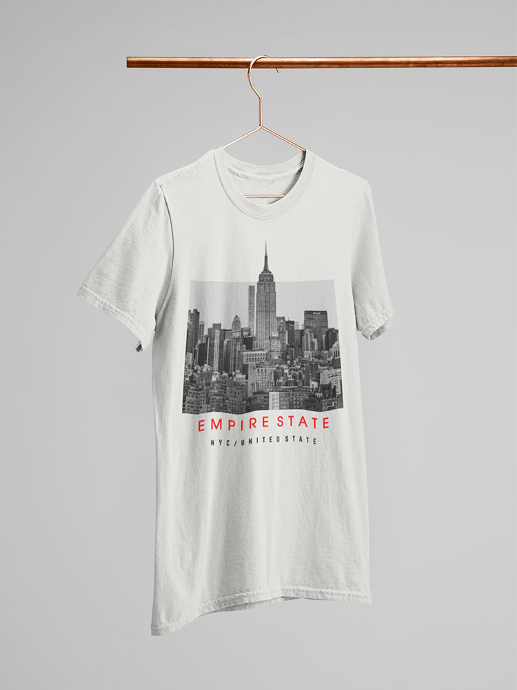White t-shirt with Empire State Building print hanging on a copper hanger against a light background. "Empire State" text featured below the building.