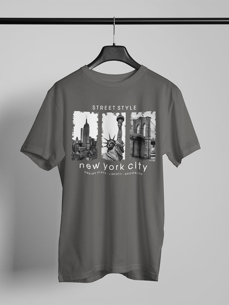 A gray T-shirt hangs on a hanger against a white background, featuring a black and white New York City themed print with landmark images.