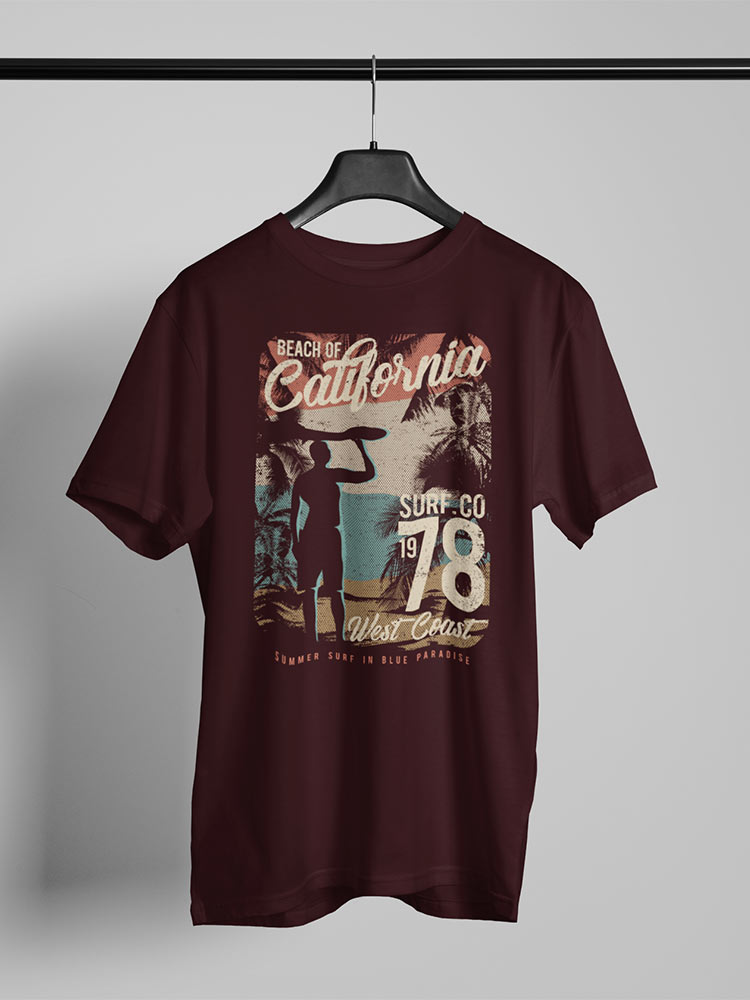 A maroon t-shirt with a California beach theme print, hanging on a hanger, with palm trees and surf-inspired graphics.