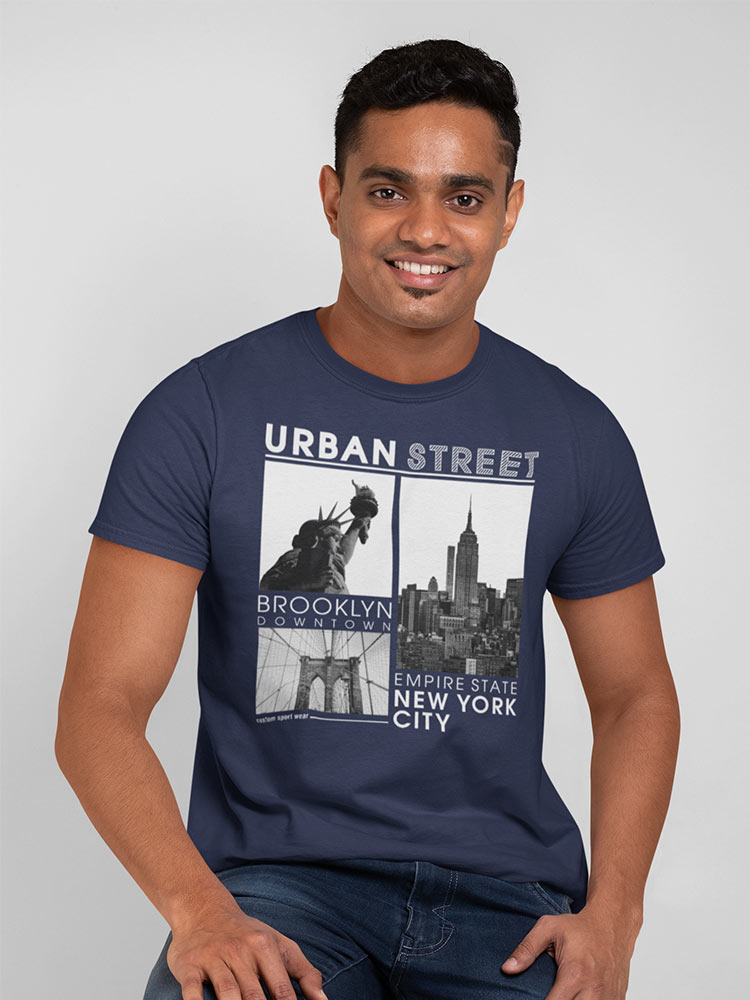 A smiling person wearing a blue t-shirt with New York City landmarks and text "Urban Street Brooklyn Downtown Empire State New York City" printed on it.