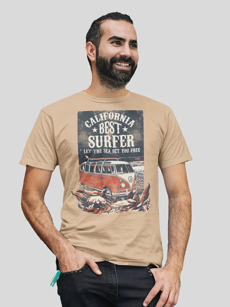 A person is smiling, wearing a beige t-shirt with a "California Best Surfer" graphic featuring a van and surfboards. The background is plain.