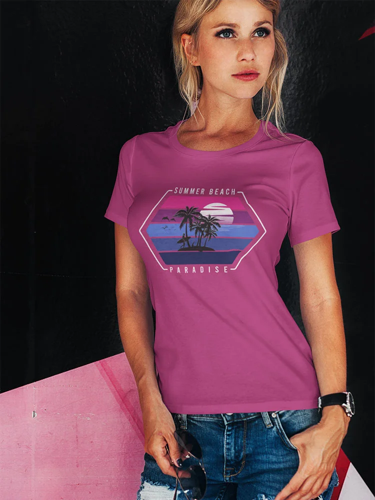 A person is wearing a pink t-shirt with a tropical beach design, standing against a contrasting black and pink backdrop, holding sunglasses.