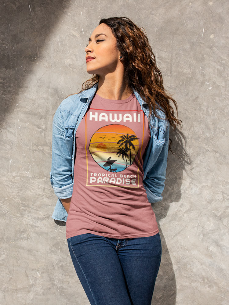 A person stands against a textured background, wearing a denim jacket, a Hawaii-themed t-shirt, and jeans, with a relaxed, confident pose.