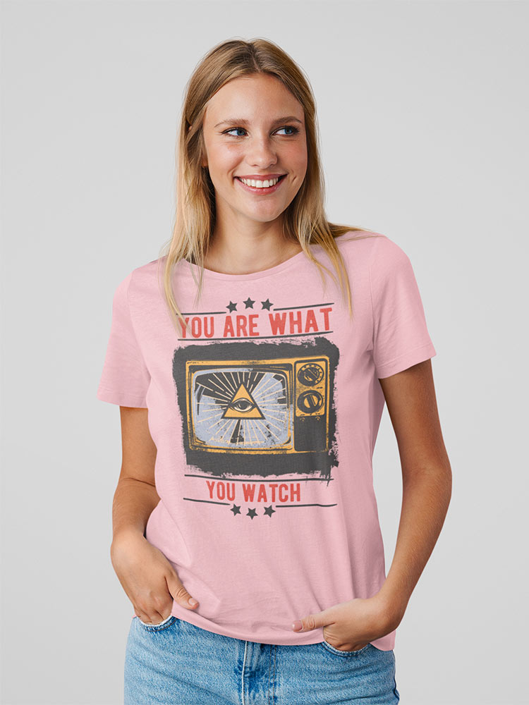 A smiling person is wearing a pink T-shirt with the text "YOU ARE WHAT YOU WATCH" surrounding a graphic of a vintage television set.