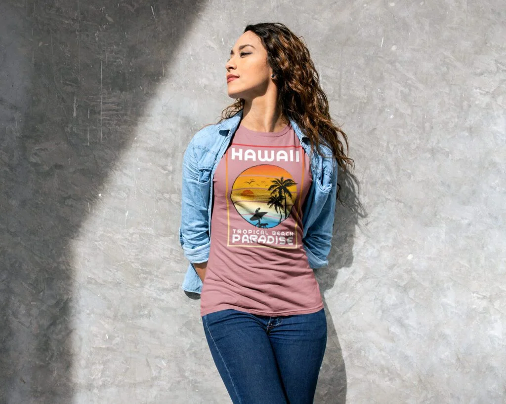 A person stands against a textured wall, wearing a Hawaii-themed T-shirt and denim jacket, eyes closed, and face tilted towards sunlight.